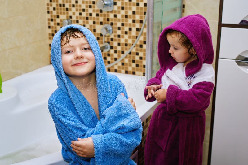 Brother and sister in the bathroom in bright robes. Brother and sister in the bathroom in bright robes