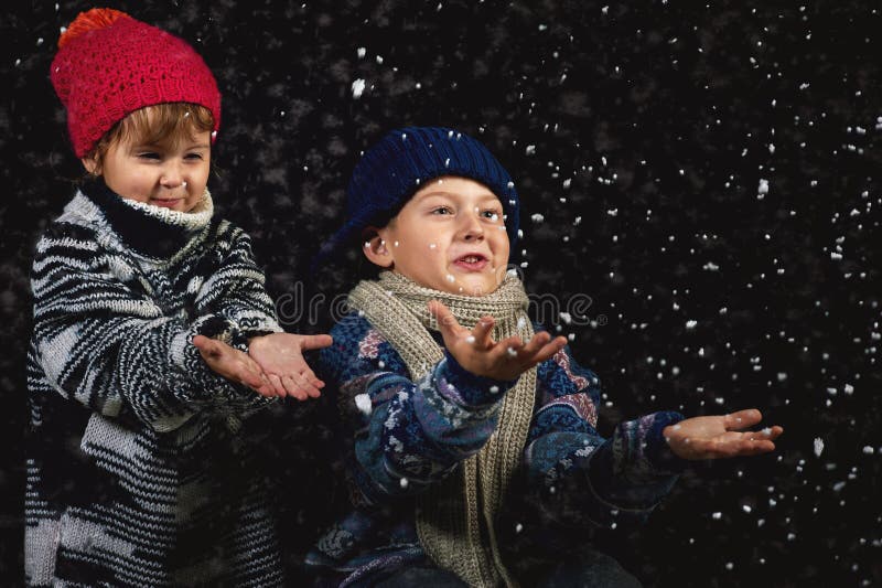 Crianças felizes que jogam com os flocos de neve na caminhada do inverno imagens de stock royalty free Crianças felizes que jogam com os flocos de neve na caminhada do inverno imagens de stock royalty free