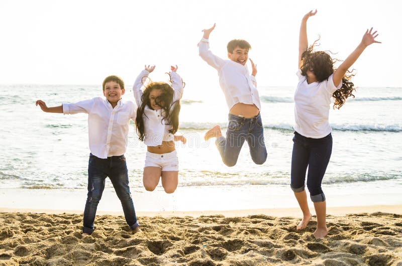 Crianças felizes que saltam junto na praia imagens de stock royalty free Crianças felizes que saltam junto na praia imagens de stock royalty free