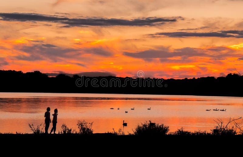 Crianças no lago durante patos de observação do por do sol imagens de stock royalty free Crianças no lago durante patos de observação do por do sol imagens de stock royalty free