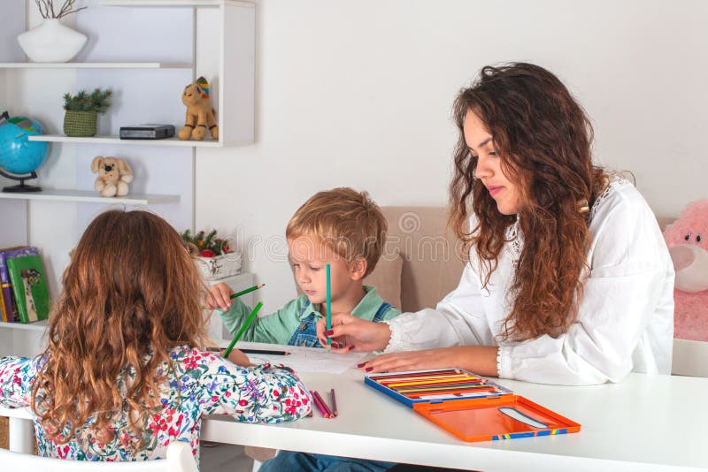 Crianças pequenas com babá estão desenhando com lápis coloridos na sala imagem de stock Crianças pequenas com babá estão desenhando com lápis coloridos na sala imagem de stock