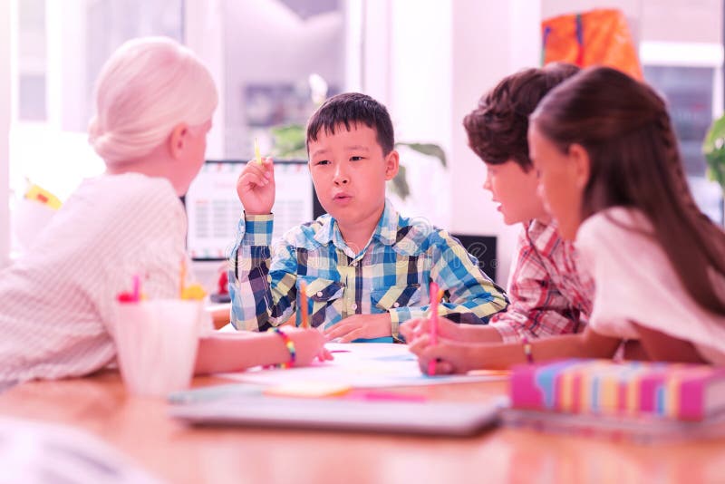 Crianças que discutem seu projeto da escola ao tirar fotografia de stock Crianças que discutem seu projeto da escola ao tirar fotografia de stock