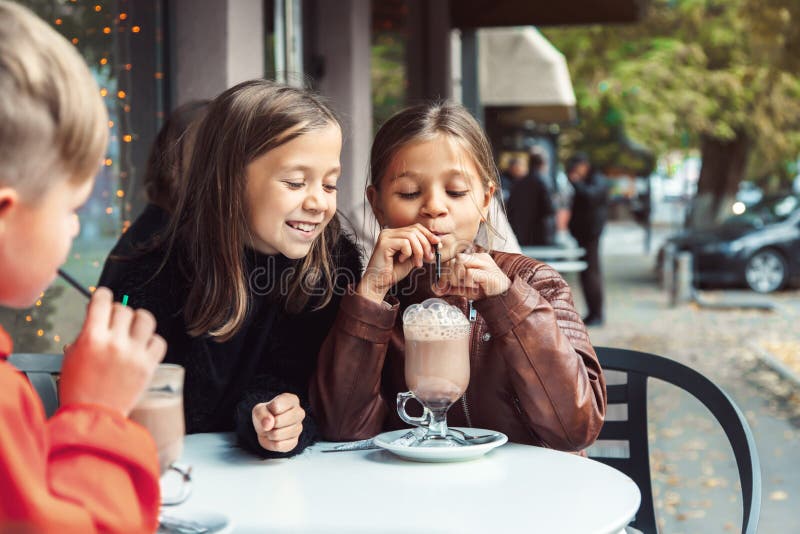 Crianças que têm o divertimento no café exterior foto de stock