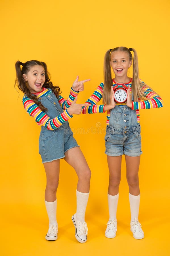 Crianças quebram conceito duas garotas alegres seguram o despertador de volta à escola verão disciplina e gerenciamento de tempo