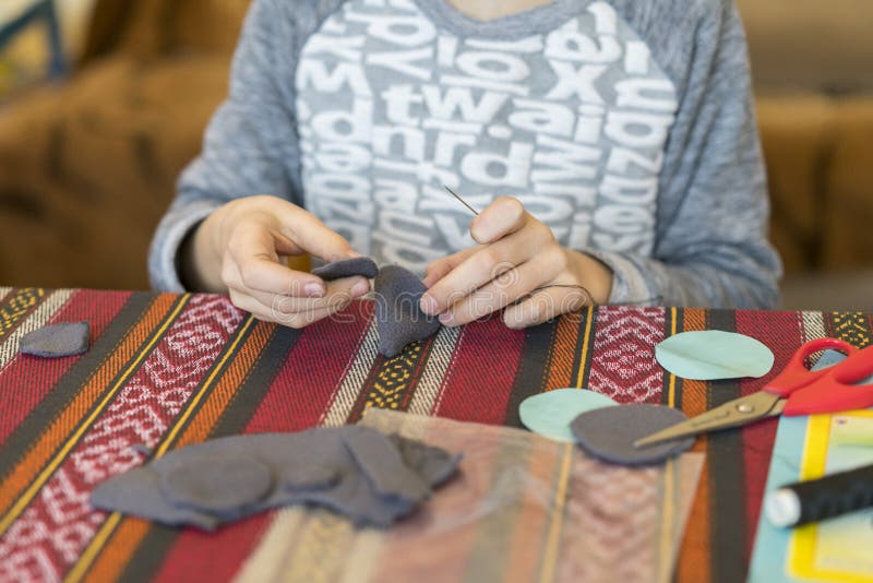 criação a menina costura o brinquedo feito do feltro A menina costura um rato cinzento A menina costura um brinquedo fotografia de stock criação a menina costura o brinquedo feito do feltro A menina costura um rato cinzento A menina costura um brinquedo fotografia de stock