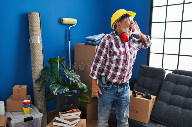Crier l'homme aîné hardhat sur les lunettes de sécurité agrafées le côté avec un cri d'oreille scintillant nouvelle folie domestiq image stock