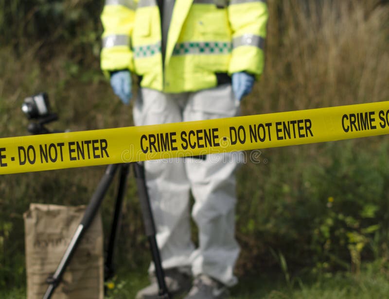 Detective checking for evidence behind a crime scene barrier. Detective checking for evidence behind a crime scene barrier