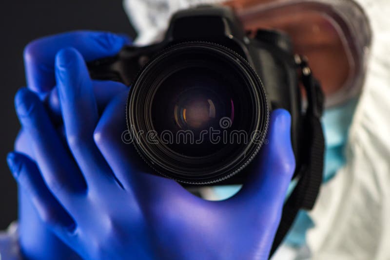 Crime scene forensics investigator with digital camera taking pictures as evidence for the investigation