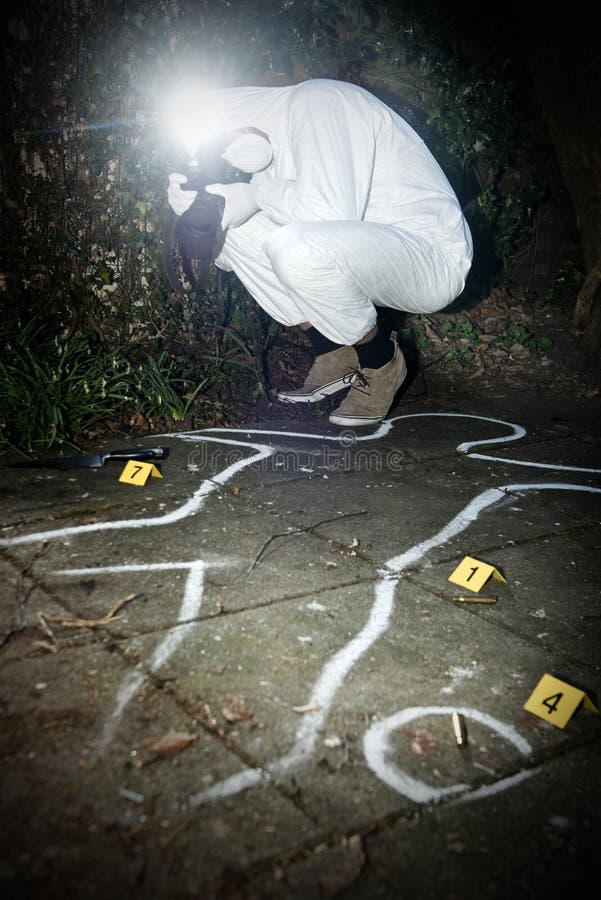 Crime scene photographer taking a photo fo during the forensics research of a murder in a park