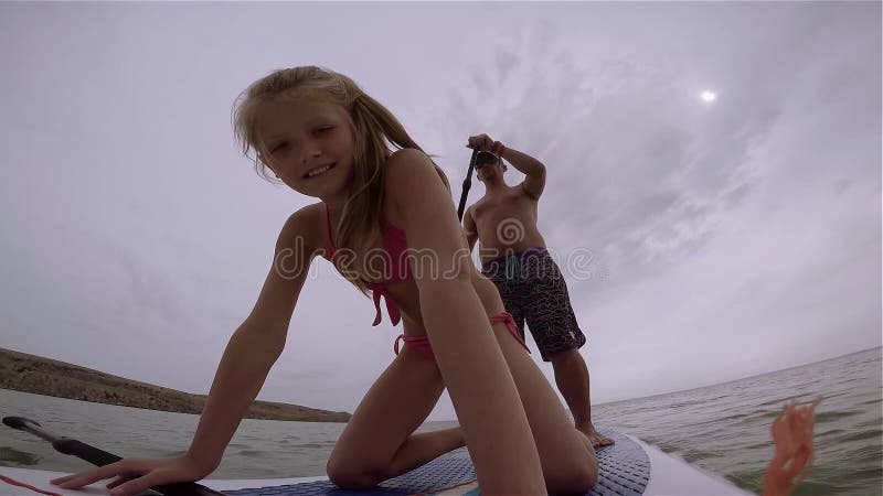 CRIMEA, UKRAIN - CIRCA AUGUST 2014: Young Girl with Her Father Ride on Paddle Board. Mainly Cloudy. Cam on the Board. Stock Footage - Video of balance, cloudy: 115471968 