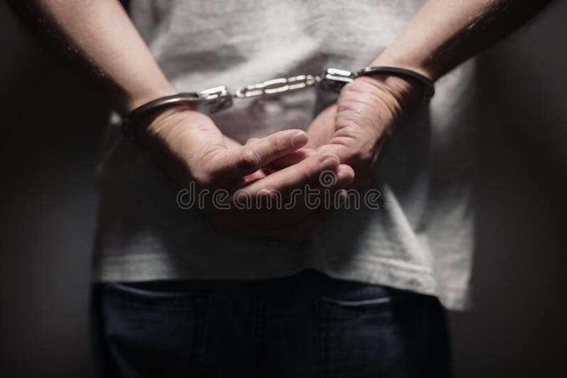 Arrested man in handcuffs with handcuffed hands behind back. Arrested man in handcuffs with handcuffed hands behind back