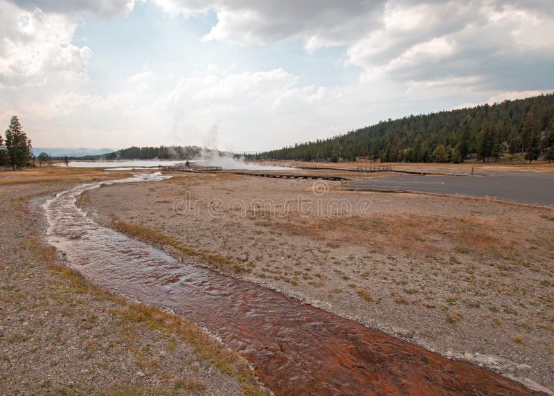 Crique embrouillée fonctionnant dans le lac chaud sous le cloudscape de cumulus dans le bassin inférieur de geyser en parc nation photo libre de droits Crique embrouillée fonctionnant dans le lac chaud sous le cloudscape de cumulus dans le bassin inférieur de geyser en parc nation photo libre de droits