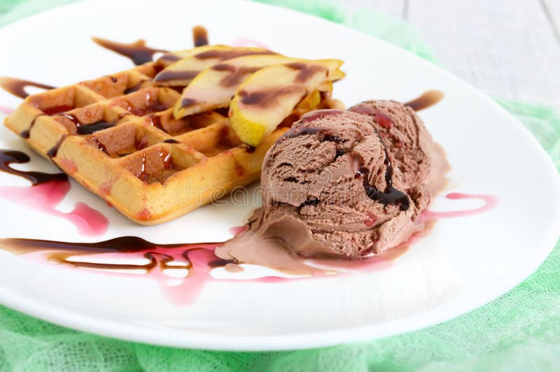 Crispy Belgian waffle with pieces of pear, berry and chocolate syrup and ice cream balls