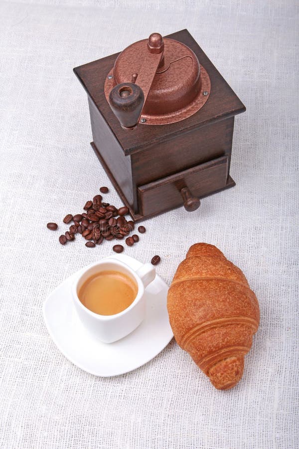 Crispy fresh croissants, cup of coffee espresso and coffee grinder on a white background, morning breakfast, selective