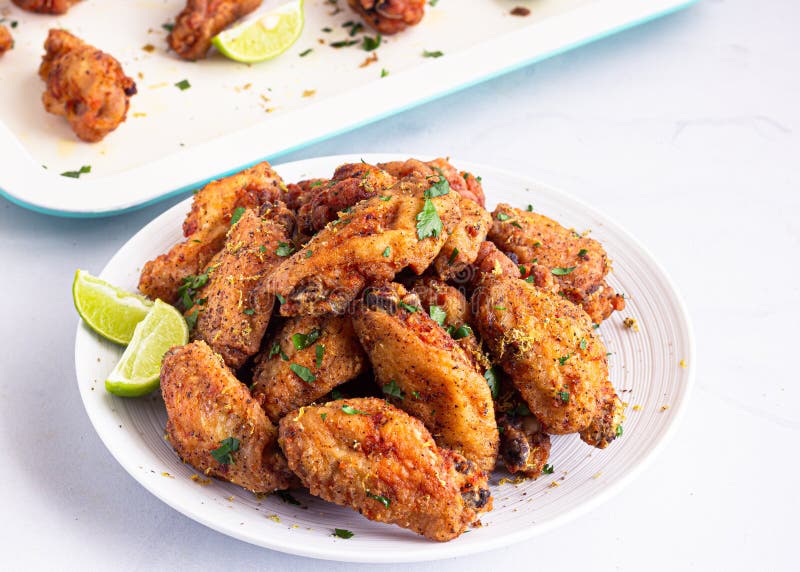 Crunchy Fried Chicken Wings on a White Plate with Lemon Wedges Stock ...