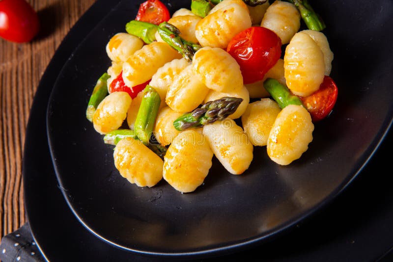 A Crispy Gnocchi with Roasted Asparagus and Tomatoes Stock Photo