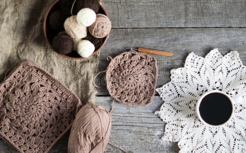 Crochet Process from Soft Woolen Yarn of Brown Color. Woolen Yarn on a Wooden Background Stock