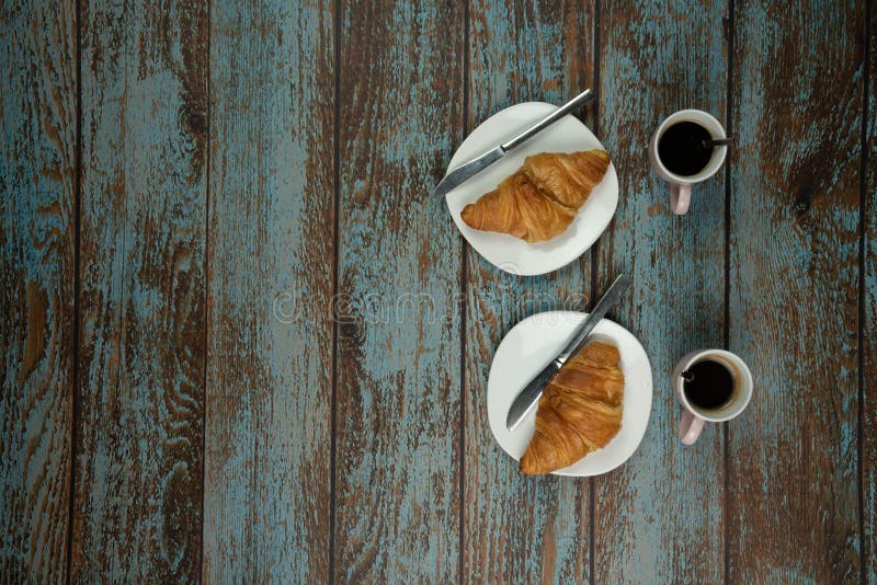 Croissant di recente al forno con caffè su un vecchio fondo di legno d'annata con spazio accanto per testo fotografie stock Croissant di recente al forno con caffè su un vecchio fondo di legno d'annata con spazio accanto per testo fotografie stock