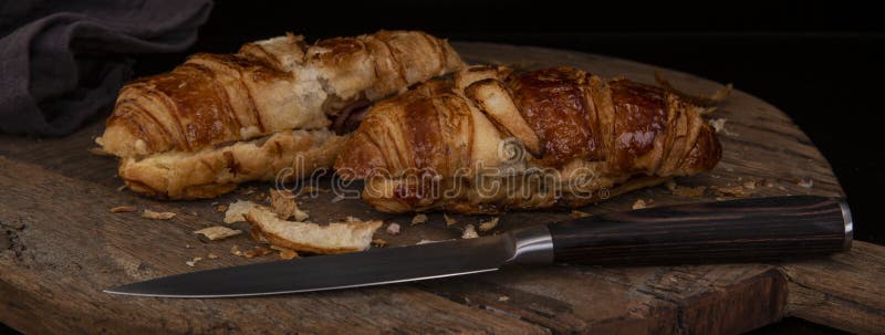 Croissant do queijo e do bacon em uma placa de corte de madeira fotografia de stock Croissant do queijo e do bacon em uma placa de corte de madeira fotografia de stock