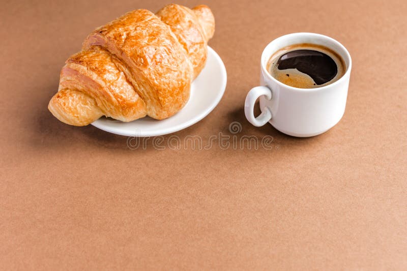 Croissant français de breackfast savoureux servi du plat et de la tasse blancs de café noir ou d'expresso sur le fond brun Copiez images stock Croissant français de breackfast savoureux servi du plat et de la tasse blancs de café noir ou d'expresso sur le fond brun Copiez images stock