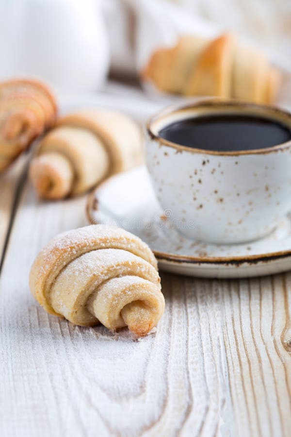 Croissant shaped cookie with a cup of coffee