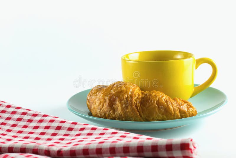 Croissant sur le plat vert avec le blanc alternatif jaune de rouge de café et de tissu de tasse sur le fond blanc