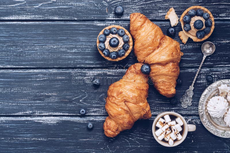 Croissants on a blue rustic wooden background, cake with blueberries, meringues. stock photos Croissants on a blue rustic wooden background, cake with blueberries, meringues. stock photos