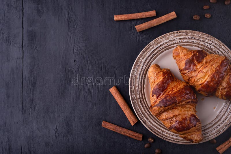 Croissants op een keramische plaat, kaneelstokken en koffiebonen op een zwarte houten tafel Bovenaanzicht met ruimte voor tekst royalty-vrije stock fotografie Croissants op een keramische plaat, kaneelstokken en koffiebonen op een zwarte houten tafel Bovenaanzicht met ruimte voor tekst royalty-vrije stock fotografie