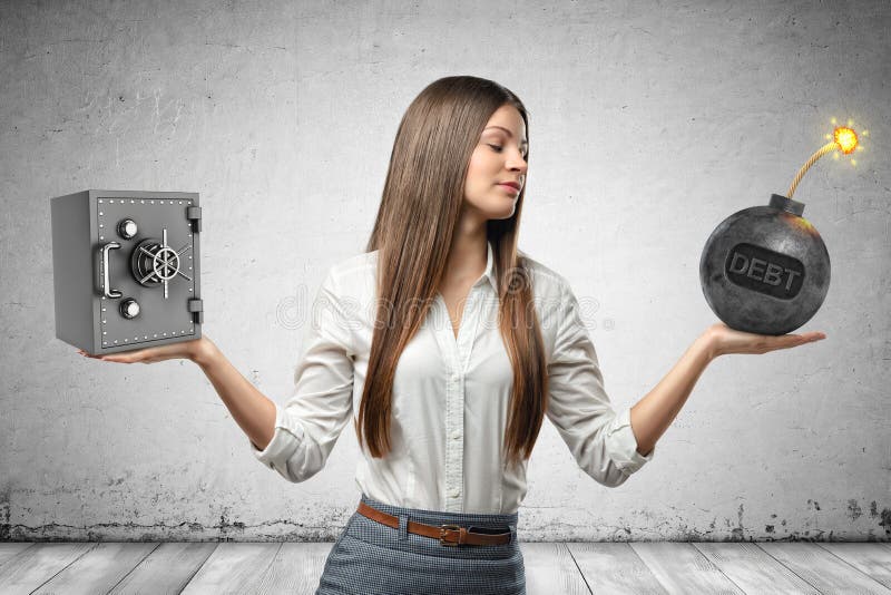 Crop image of young beautiful businesswoman holding little money safe in one hand and ball bomb with word DEBT on it in