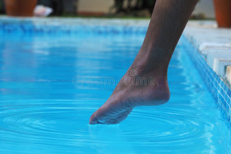Tanned man legs try to swim on outdoors swimming pool.
