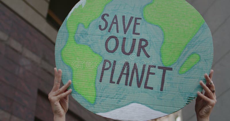 Crop view of person raising Earth model with writing save our planet. Female hands holding placard while striking