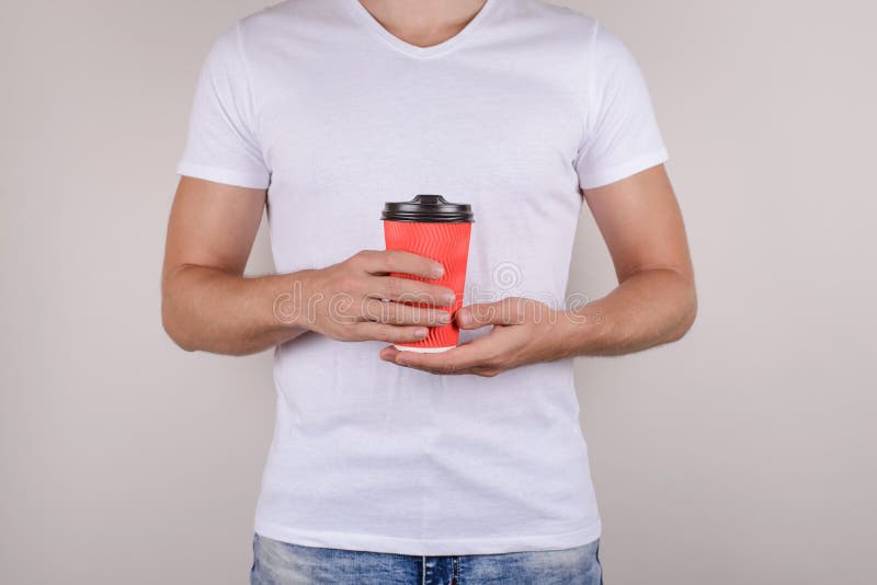 Cropped close up photo of bright vivid red cup with cap brown plastic lid in hands of handsome mach virile masculine cool man royalty free stock image Cropped close up photo of bright vivid red cup with cap brown plastic lid in hands of handsome mach virile masculine cool man royalty free stock image