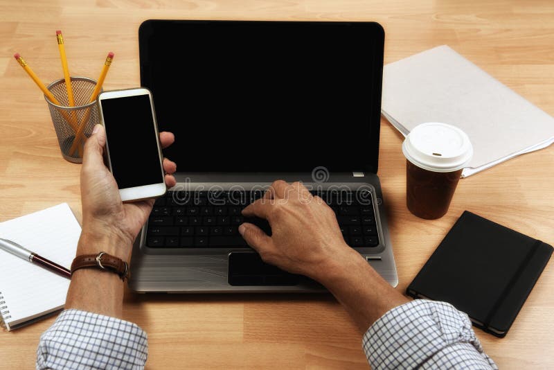 Cropped high angle shot of a businessman using a computer and cell phone while working at home royalty free stock photography