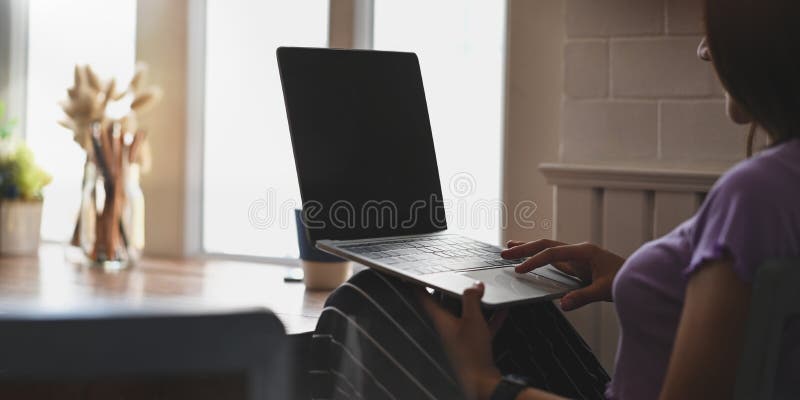 Cropped image of beautiful woman working with computer laptop that putting on her lap.