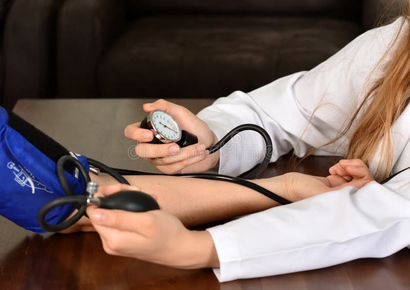 Cropped image of Female doctor checking blood pressure of patient at table stock photography Cropped image of Female doctor checking blood pressure of patient at table stock photography