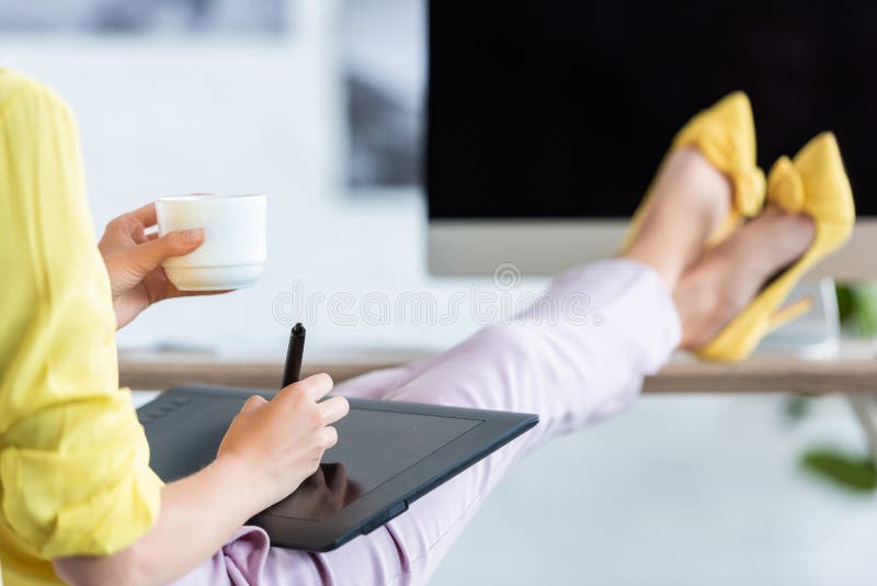 cropped image of female freelancer drinking coffee and using graphic tablet at table with computer royalty free stock photos cropped image of female freelancer drinking coffee and using graphic tablet at table with computer royalty free stock photos