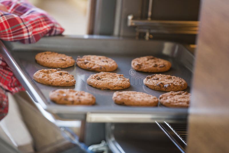 Cropped image of hand removing cookie tray from oven in kitchen stock photo Cropped image of hand removing cookie tray from oven in kitchen stock photo