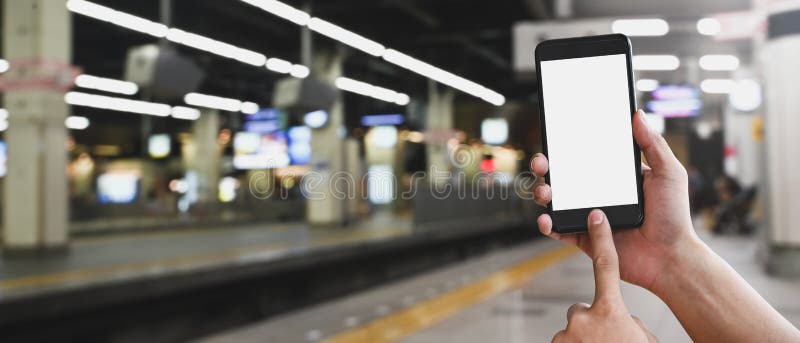 Cropped image of hands is using a white blank screen smartphone at the subway. stock photo