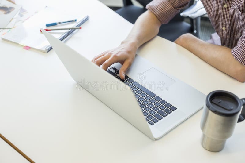 Cropped image of man using laptop at desk in creative office stock photo