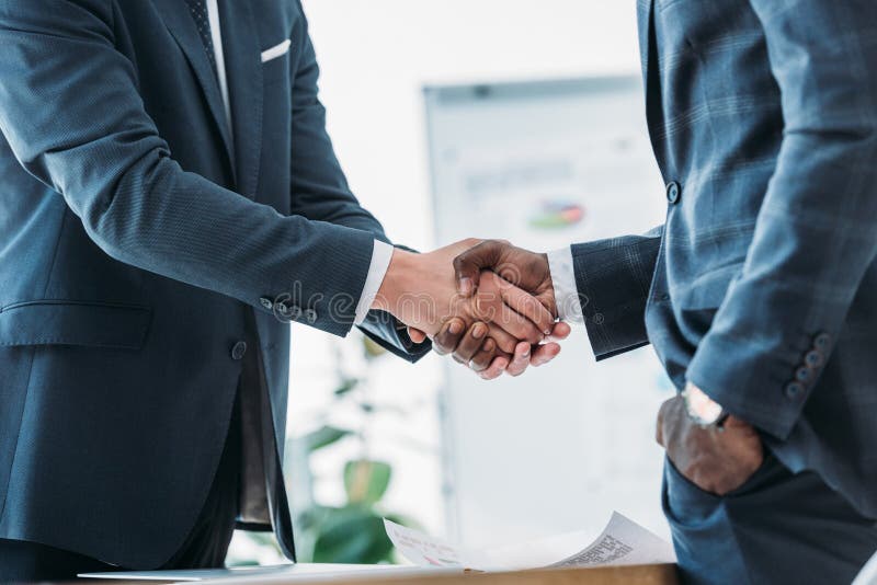 Cropped Image of Multicultural Businessmen in Suits Shaking Hands Stock