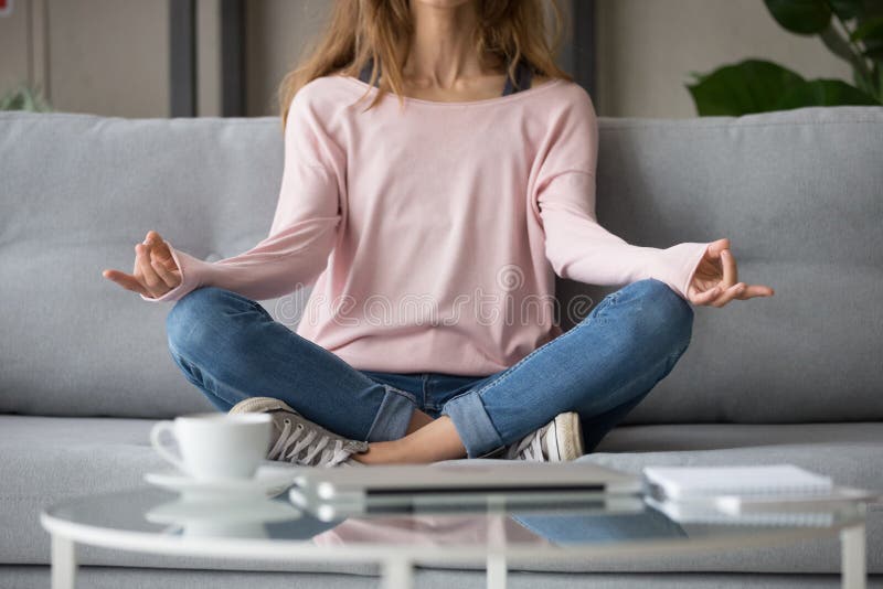 Cropped image woman sitting on couch in lotus pose meditating royalty free stock photography Cropped image woman sitting on couch in lotus pose meditating royalty free stock photography