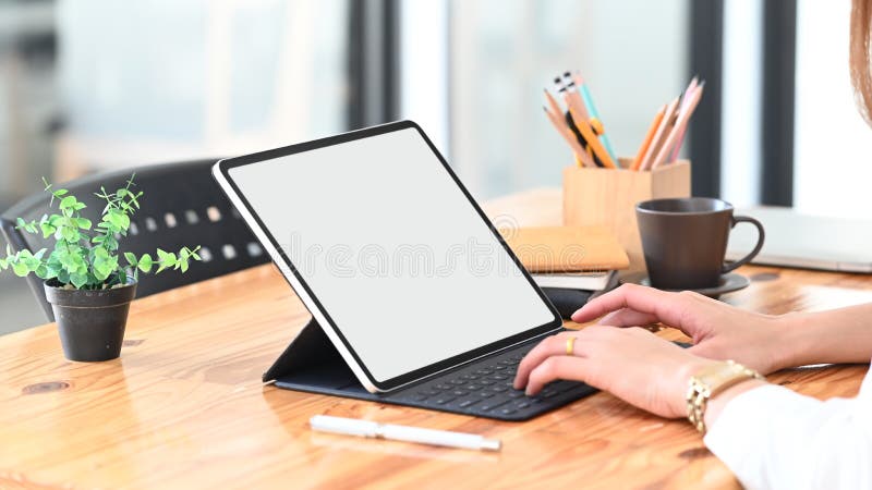 Cropped image of young beautiful woman working as secretary sitting and typing on white blank screen computer tablet.