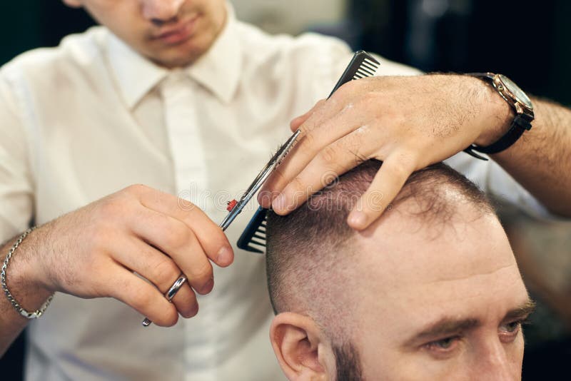 Male hairdresser making short haircut for client in modern barbershop. Concept of traditional haircutting with scissors. stock images Male hairdresser making short haircut for client in modern barbershop. Concept of traditional haircutting with scissors. stock images