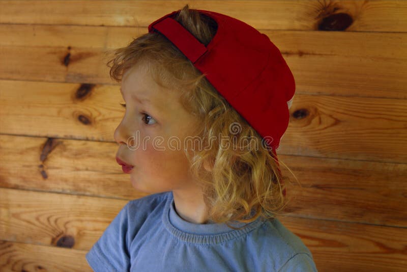 Cropped Shot Of A Cute Little Baby Boy With Curly Hair Wearing Red Hat