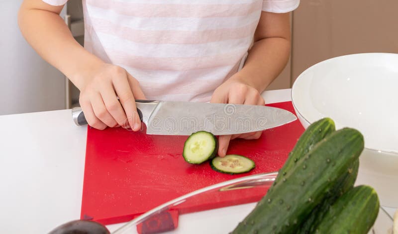 Cropped Shot of Girl Cutting Cucumber with Knife on a Table in Kitchen ...