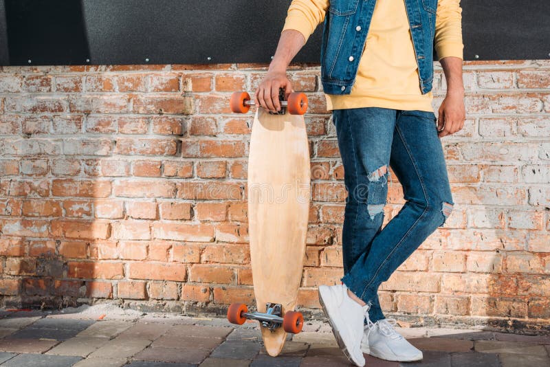 cropped shot of man with longboard standing.