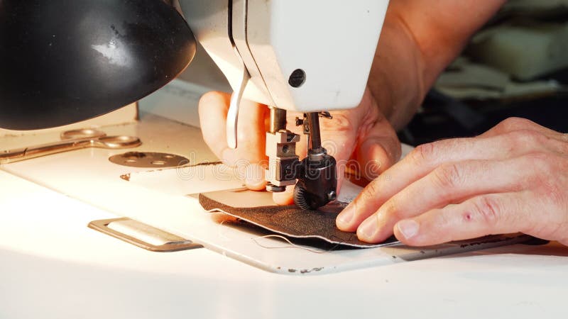 Shoemaker using vintage sewing machine at his workshop stock video footage