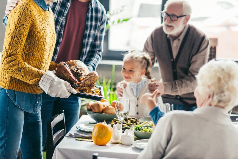 Cropped shot of man and woman carrying turkey for thanksgiving dinner while excited family looking stock photos Cropped shot of man and woman carrying turkey for thanksgiving dinner while excited family looking stock photos