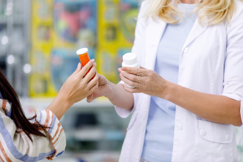 cropped shot of pharmacist and customer holding containers with medication stock photo cropped shot of pharmacist and customer holding containers with medication stock photo