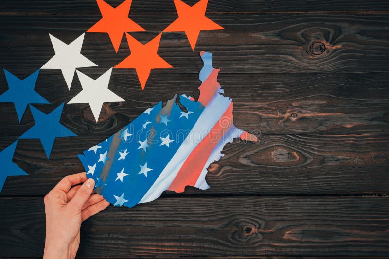 Cropped shot of stars and female hand with piece of map with american flag on wooden tabletop stock photos Cropped shot of stars and female hand with piece of map with american flag on wooden tabletop stock photos